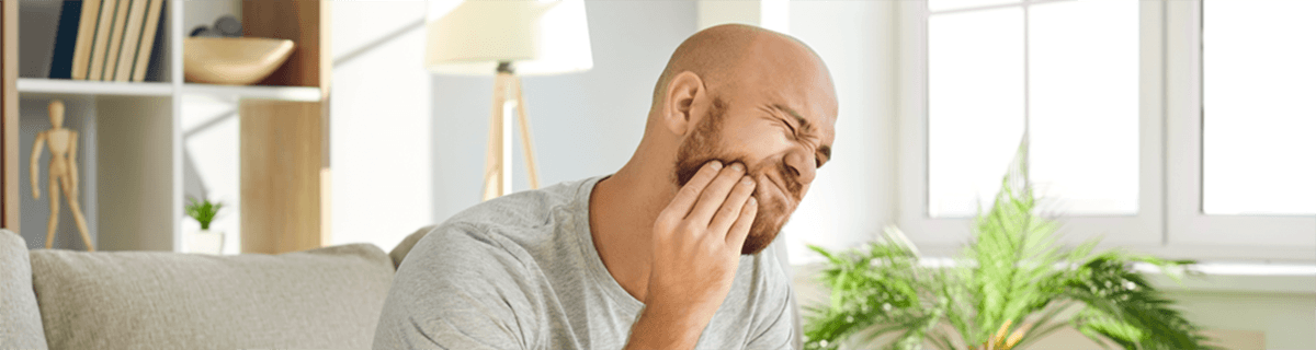 Patient in Shelbyville holding their cheek due to dental implant failure