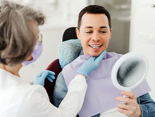 Man smiling at reflection in mirror with dentist