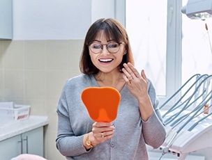 Dental patient holding mirror and smiling