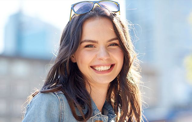 Brunette woman with sunglasses smiling outdoors