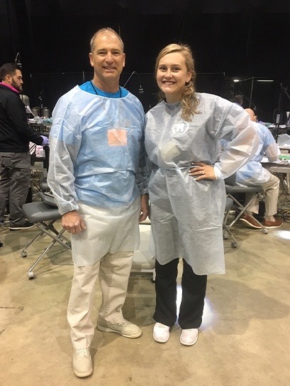 Dentist and team member wearing scrubs at community event