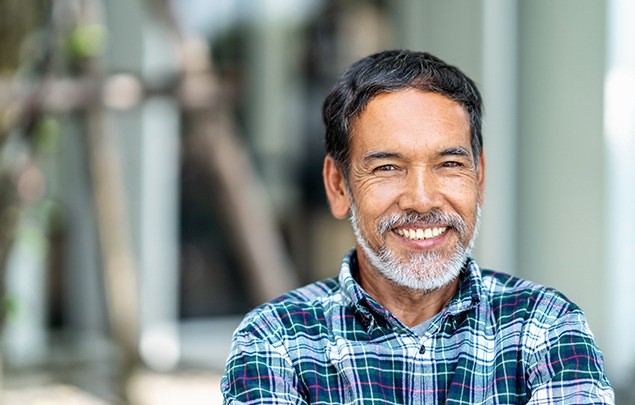 Older man in blue plaid shirt smiling