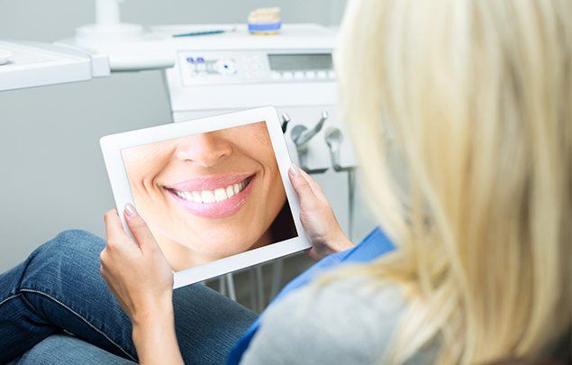 Woman looking at tablet screen showing close up of smile with flawless teeth