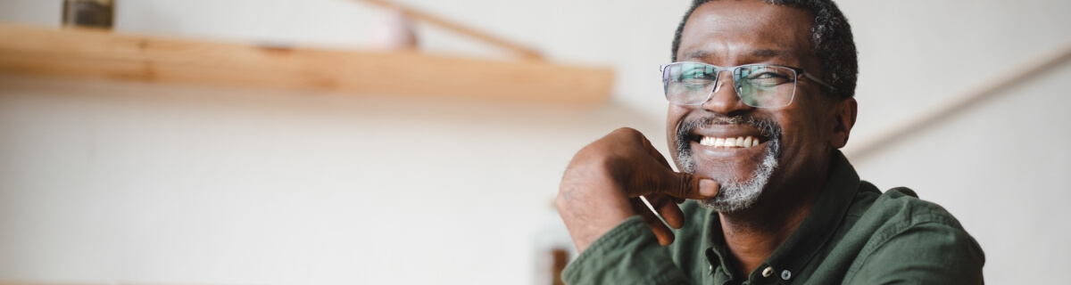 Senior man sitting at table and smiling with dentures in Selbyville