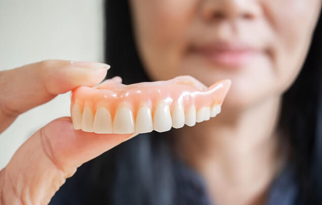 Close up of woman holding a denture