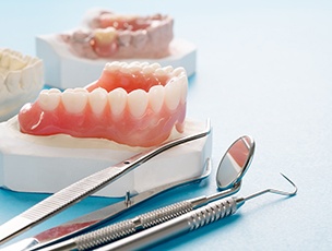 Set of lower dentures on a cast next to dental instruments