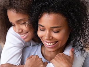 Mother and daughter smiling and hugging