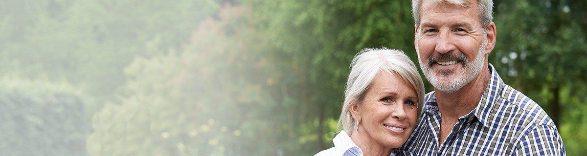 Older man and woman smiling together outdoors with dental implants in Selbyville