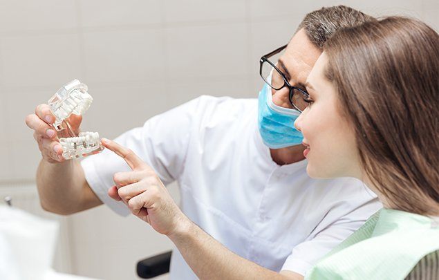 Dentist showing a patient a dental implant model