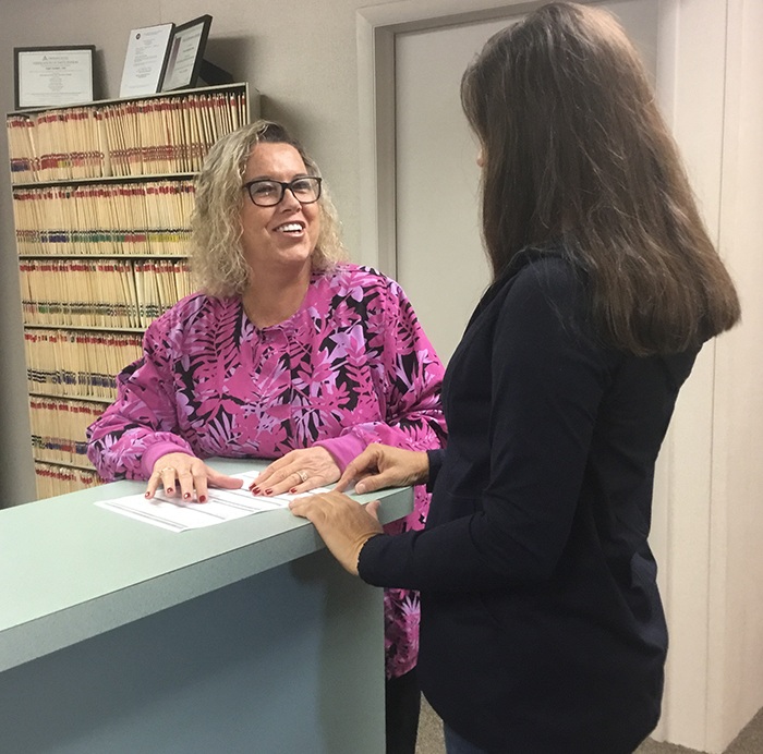 Two team members talking at dental office reception desk