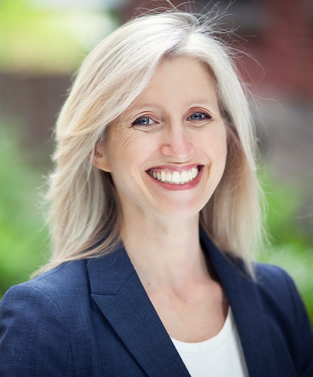 Woman in suit jacket grinning outdoors