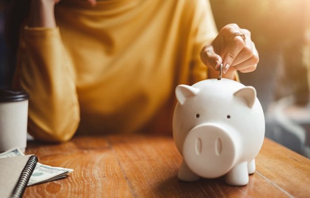 a person putting a coin in a piggy bank