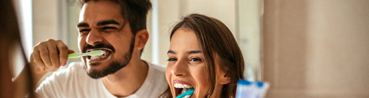 A man and woman brushing their teeth together with Invisalign in Selbyville