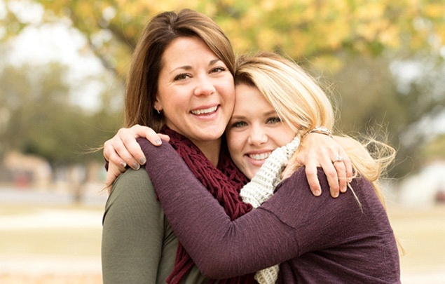 A mother and daughter hugging outside