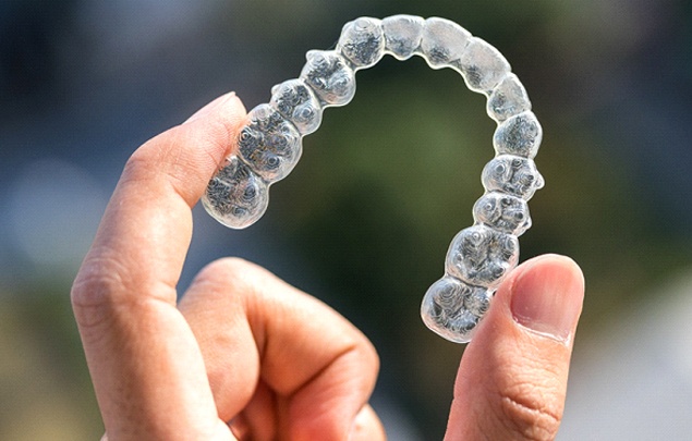 A person holding a clear aligner for Invisalign