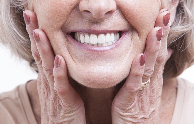 Older woman smiling and touching her face