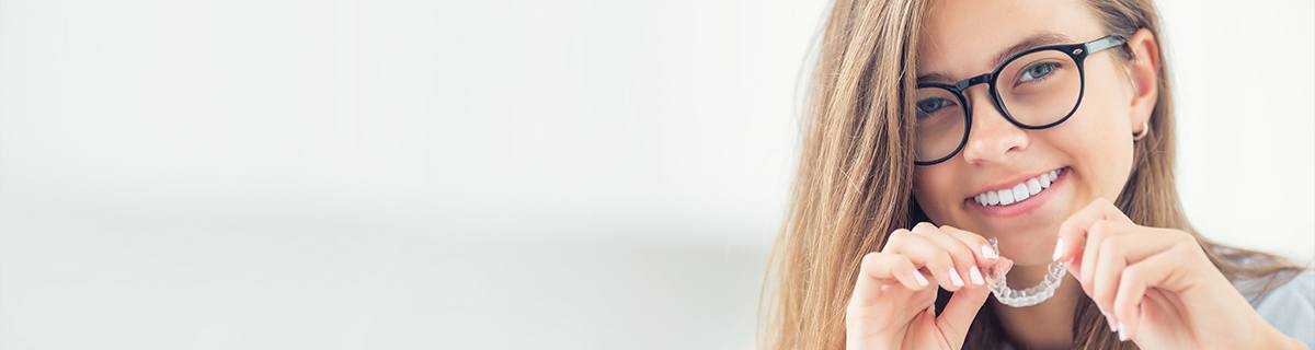 Young woman placing Invisalign tray in her mouth