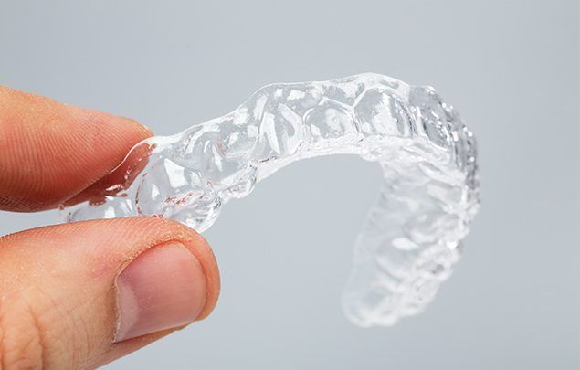 Hand holding an Invisalign tray