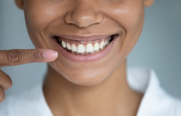 Close up of woman pointing to her smile