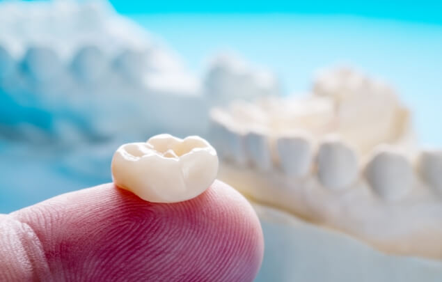 Close up of a dental crown resting on a finger