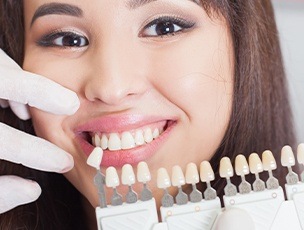 Woman smiling next to tooth color chart