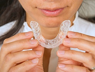 Woman holding clear aligner tray near her mouth