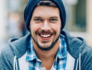 Young man with beard and beanie smiling