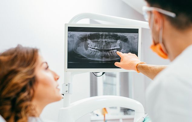 Dentist and patient looking at digital x rays of teeth