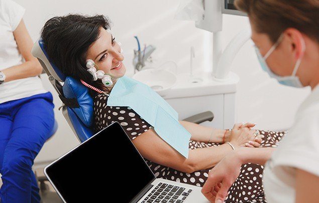 Woman in dental chair smiling at dentist