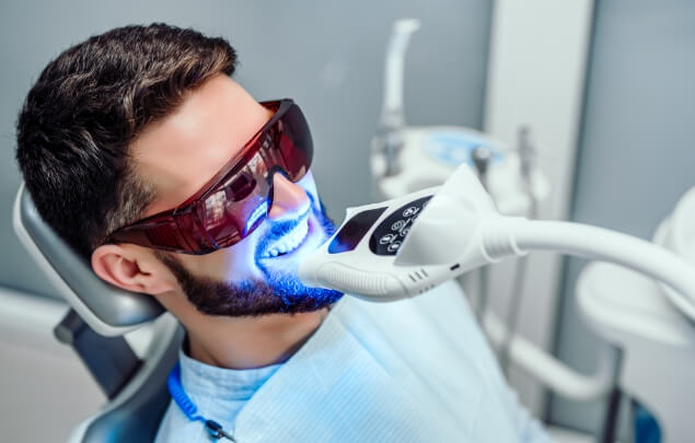 Man in dental chair getting his teeth professionally whitened