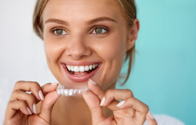 Smiling woman holding a teeth whitening tray