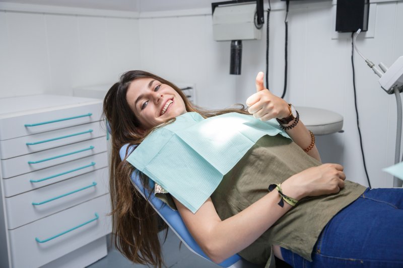 woman giving thumb up dentist chair