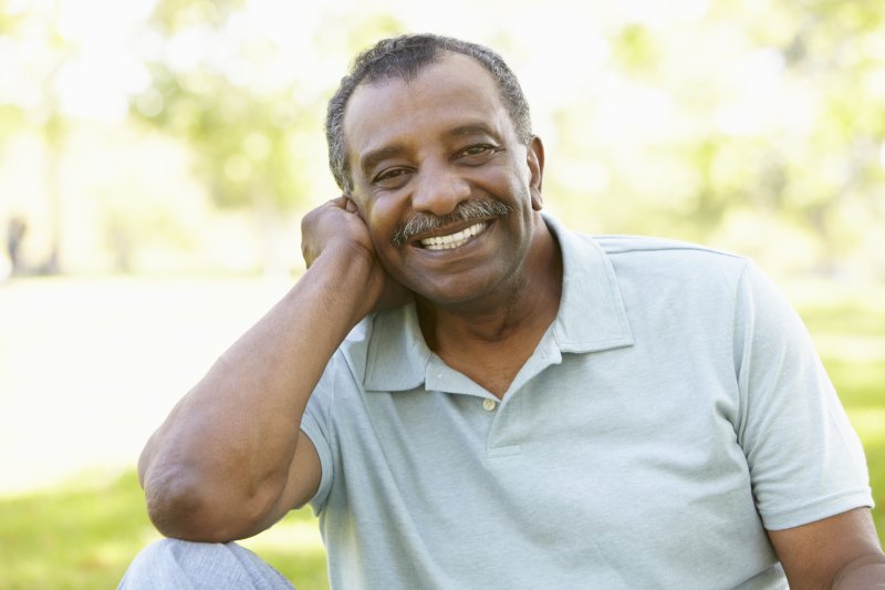 older man smiling confidently after receiving dental implants