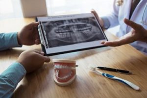 Dentist sitting at a desk speaking to patient about an X-ray