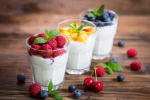 Three small glasses of yogurt topped with fruit