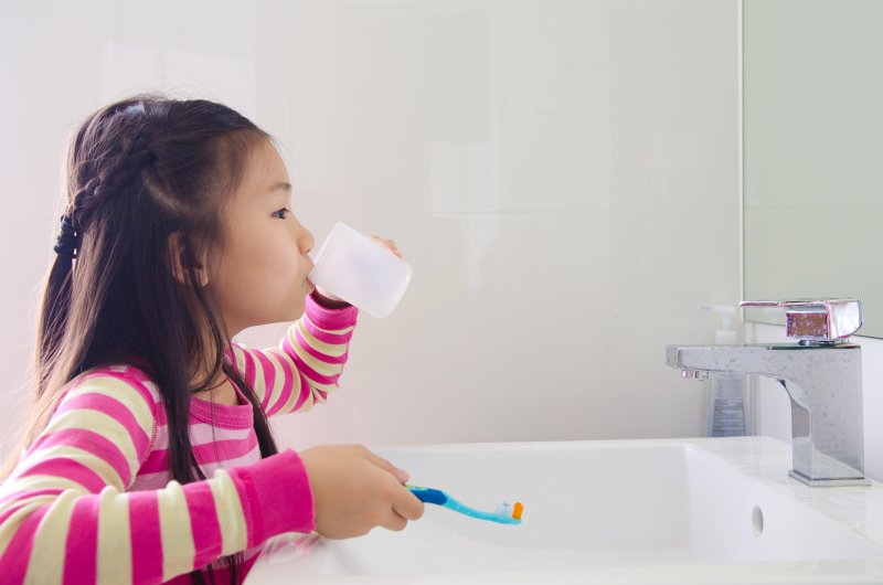 girl rinsing her mouth after brushing teeth