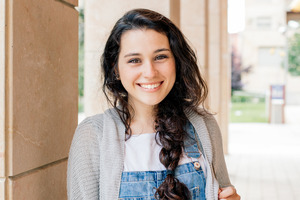 Teenage girl in overalls and sweater smiling