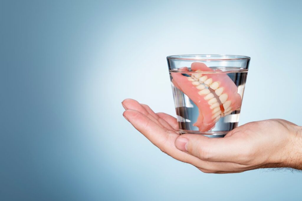 A pair of dentures soaking in a glass of water.