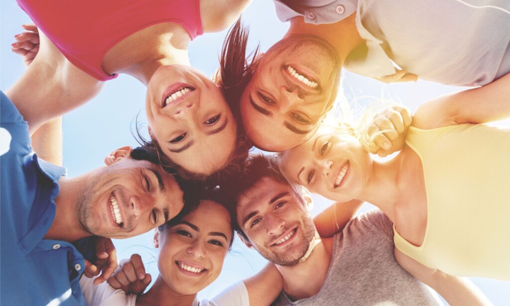 Diverse group of people huddled together smiling